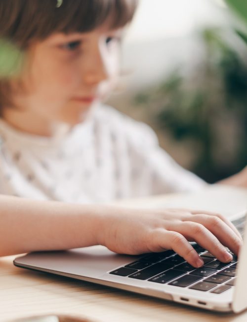 Distance learning online education. Caucasian smile kid boy studying at home with laptop and doing school homework. Thinking child siting at table with notebook. Back to school.