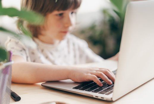 Distance learning online education. Caucasian smile kid boy studying at home with laptop and doing school homework. Thinking child siting at table with notebook. Back to school.